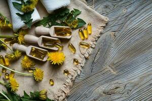 Softgels of dandelion extract on wooden spoons. photo