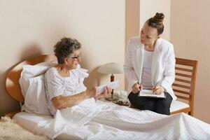 Visit of senior social work assistant to an old woman photo