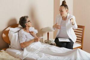 Young lady explains how to work with remote control to an old woman photo