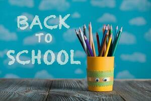 Yellow pencils holder with colorful school supplies on a wooden surface. photo