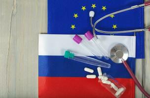 Medication,test tubes,money and stethoscope on European and Russian flags photo