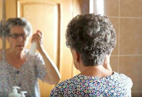 Old woman is combing her hair photo