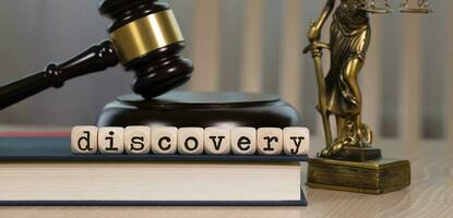 Word DISCOVERY composed of wooden dices. Wooden gavel and statue of Themis in the background. photo