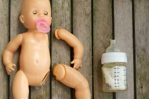 Abandoned plastic doll on wooden surface photo