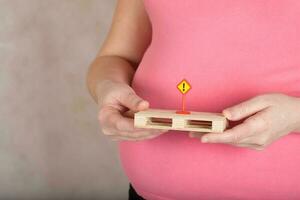 Young pregnant woman keeps sign exclamation mark. photo