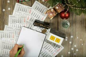 Blank sheet of paper and small paper house with coins on the New Year's background. photo