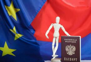 Russian pass and wooden dummy figurine on Russian and European flag. photo
