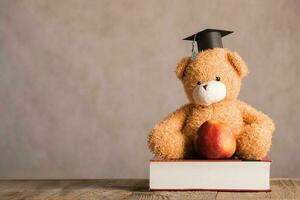 Brown teddy bear in an academic cap is placed on a thick dictionary. photo