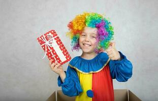 chico de cinco años vestido en el disfraz de un payaso con un regalo. foto