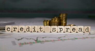 Words CREDIT SPREAD composed of wooden letter. Stacks of coins in the background. photo