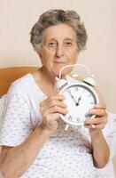 Old woman with vintage alarm clock photo