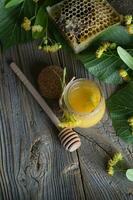 Linden blossoms honey in a glass bottle on a wooden surface. photo