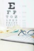 Eyeglasses for children on a eye chart close to eye pads. photo