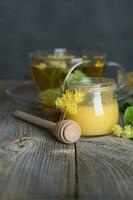 Linden blossoms honey in a glass bottle on a wooden surface. photo