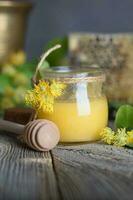 Linden blossoms honey in a glass bottle on a wooden surface. photo