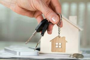 Female keeps house key on a key hanger in front of a wooden house. photo