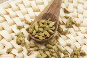 Cardamom berries in the wooden made spoon photo