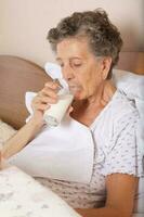 Old woman drinks some milk in the morning photo