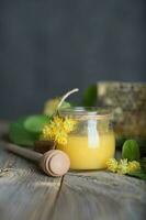 Linden blossoms honey in a glass bottle on a wooden surface. photo