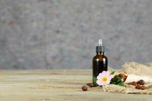 Rose hip syrup in a dark glass dropper bottle on a wooden surface. photo