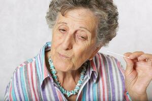Old woman is cleaning her ears with cotton swab photo