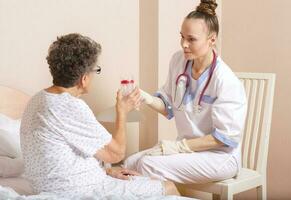 Geriatrician visits a senior woman, Medical sister gives a collection cup to old woman photo