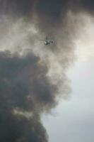 Helicopter of State Emergency Service is flying in the cloud of black smoke photo
