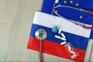 Medication and stethoscope on European and Russian flags photo