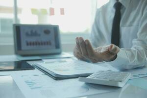 Close up businessman hand using calculator and working with laptop calculate about finance accounting at coffeeshop outdor.finance accounting concept photo