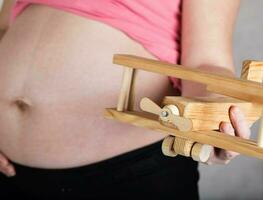 Young pregnant woman keeps wooden made airplane. photo