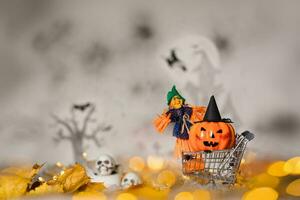 Witch and orange pumpkin in black hat in the small shopping cart. Closeup photo