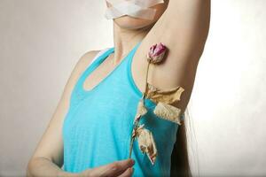 A young woman between keeps dehydrated rose close to her armpit. photo