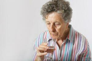 Old woman is drinking some water photo