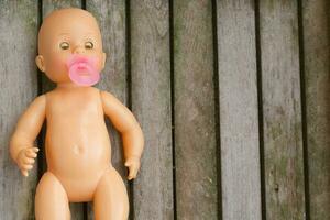 Abandoned plastic doll on wooden surface photo