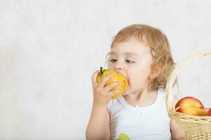 Small girl  is eating fresh fruits from a table. Closeup photo