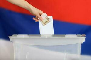 Female hand keeps ballot paper and Russian rubles above ballot box. photo