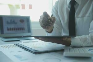 Close up businessman hand using calculator and working with laptop calculate about finance accounting at coffeeshop outdor.finance accounting concept photo