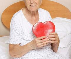 Old woman with red heart in her hands photo