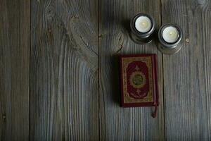 Quran and candles on a wooden surface. photo