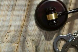 Wooden gavel and handcuff on a wooden surface. photo