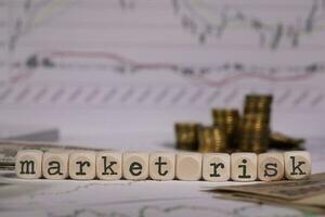 Words MARKET RISK composed of wooden letter. Stacks of coins in the background. photo