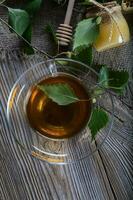 Birch leaf train a glass cup on a wooden surface. photo