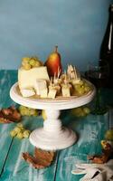 Cheese slices, pear, and grapes on a wooden stand. photo