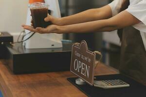 Open. barista, waitress woman wearing protection face mask turning open sign board on glass door in modern cafe coffee shop, cafe restaurant, retail store, small business owner, food and drink concept photo