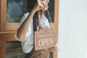 Open. barista, waitress woman wearing protection face mask turning open sign board on glass door in modern cafe coffee shop, cafe restaurant, retail store, small business owner, food and drink concept photo