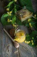 Linden blossoms honey in a glass bottle on a wooden surface. photo