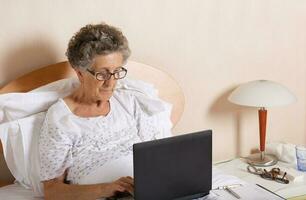 Old woman is communicating through her computer wit hrelatives photo