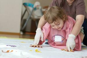 Child is painting white blanket with their palms photo