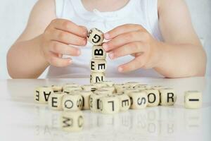 pequeño niña compone palabras desde letras. de cerca foto