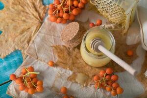 serbal bayas, vaso con miel y panal en un arpillera. . foto